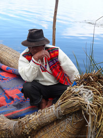 Man sits on his totora reed boat on the floating islands of Uros