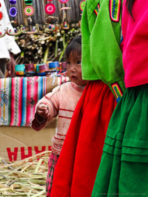 Small child peeks from behind her sisters skirts