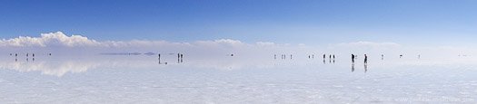 People walking across a flooded Salar de Uyuni