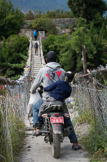 motorcycle posed to ride across wooden swing bridge