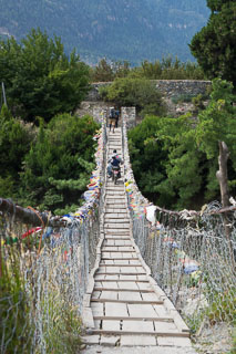 motorcycle riders crossing wooden swing bridge